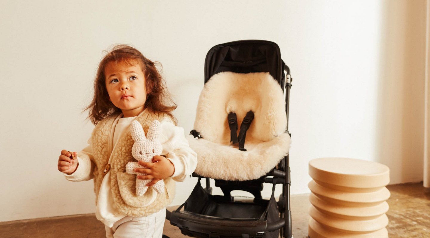 woman opening gift box on sofa containing baby gifts and gift note. gift box sits on sofa