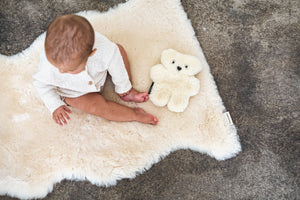 baby sat on sheepskin rug with binibear sheepskin teddy bear